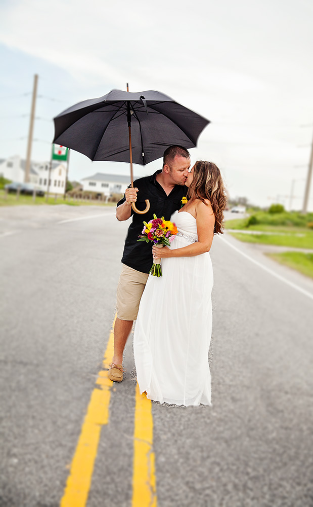 bride and groom with umbrella on beach road in Nags Head NC