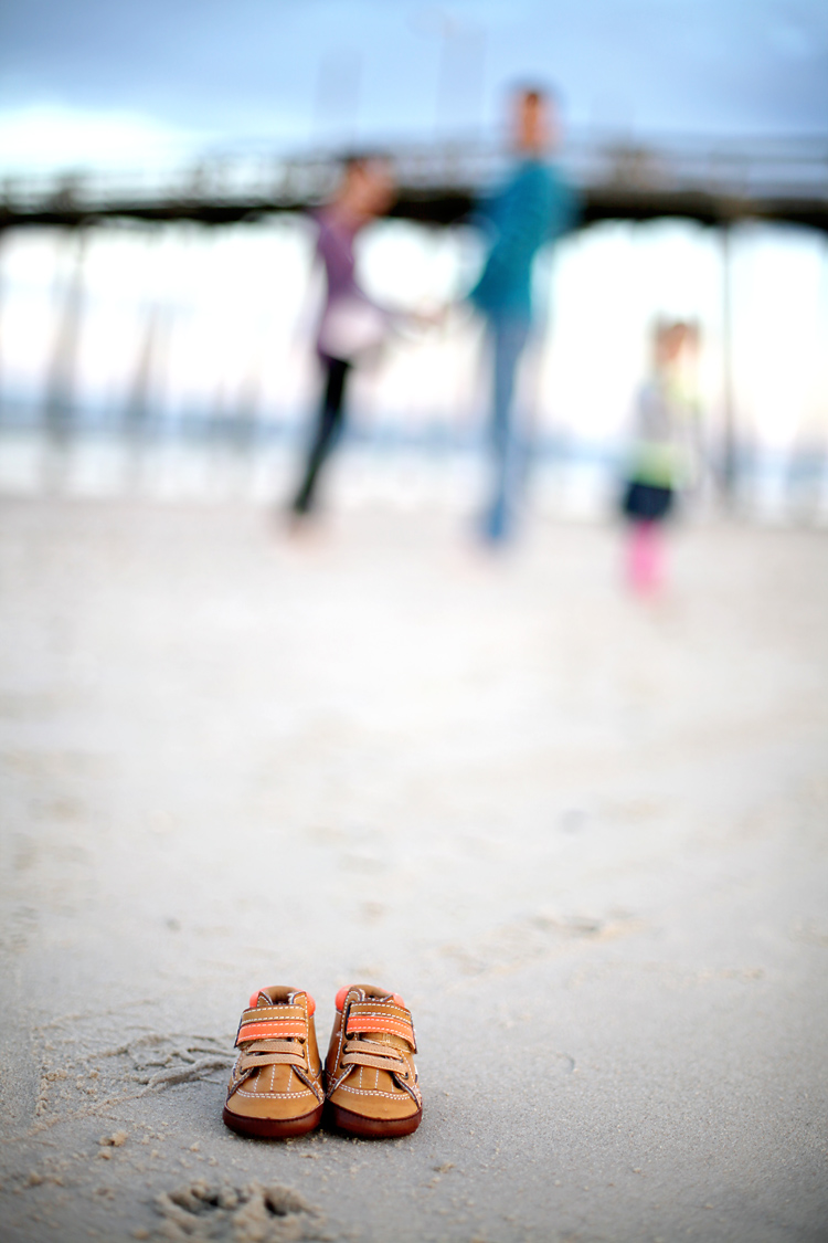 Newborn shoes with pregnant mom in background