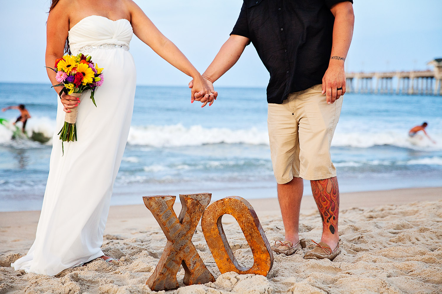 Just married couple with surfers in the background