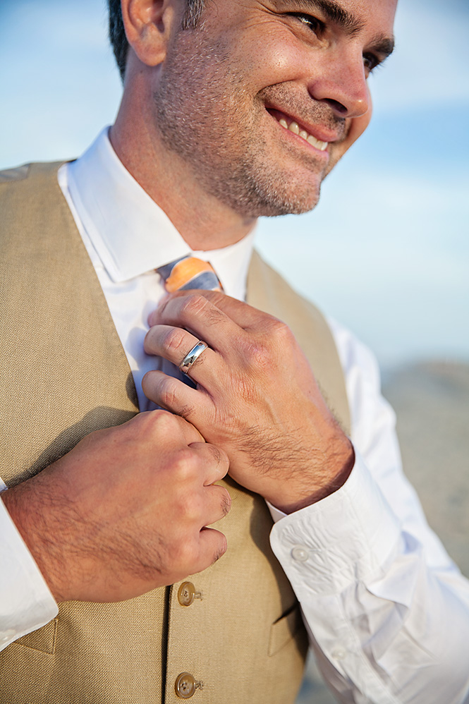 Groom straightening tie at beach in Duck NC