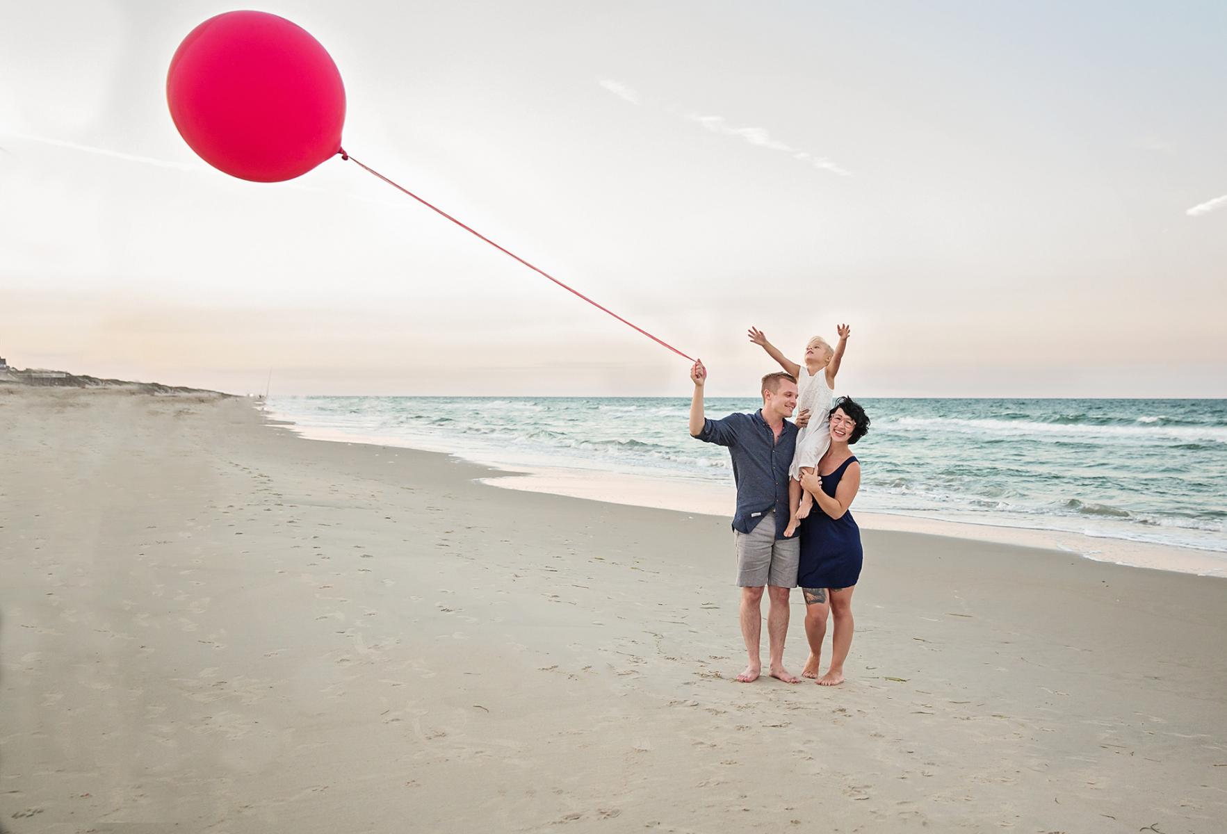 Family of 3 on beach with red balloon in Outer Banks NC