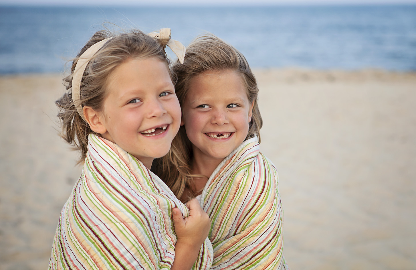 Sisters wrapped in a blanket at the beach in Nags Head NC