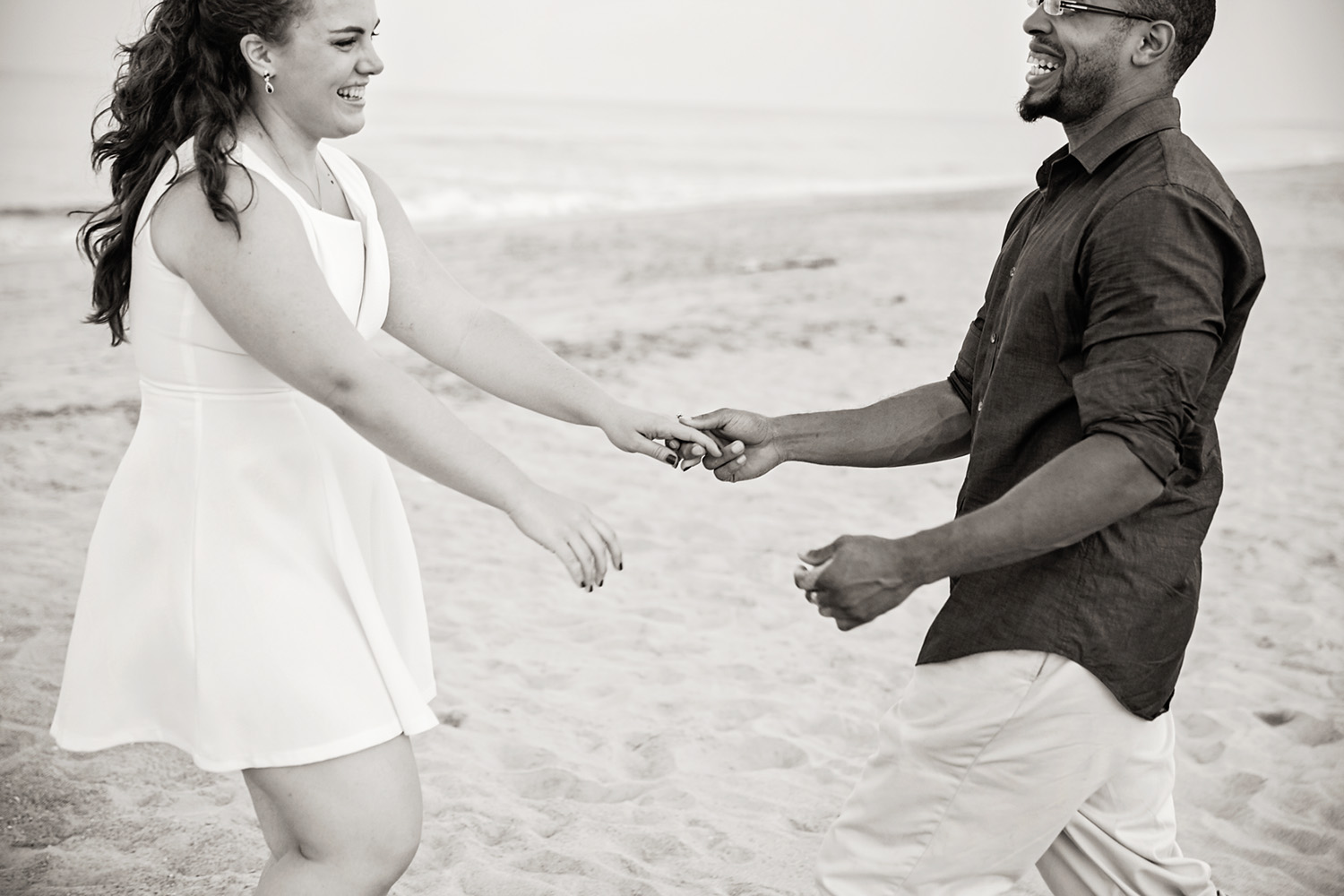 Black and white couple laughing at the beach